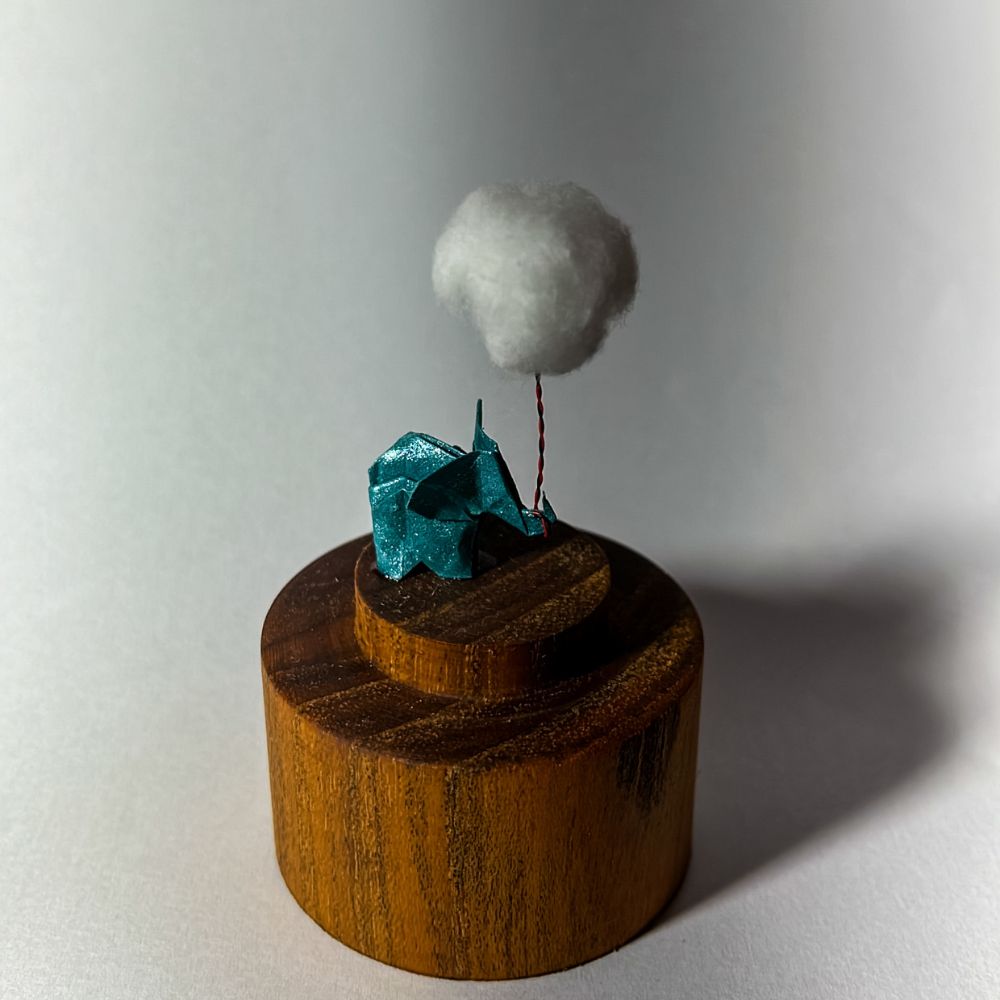 Lámpara miniatura de elefante amarillo en origami sosteniendo una nube iluminada en domo de vidrio - Plicatorius.