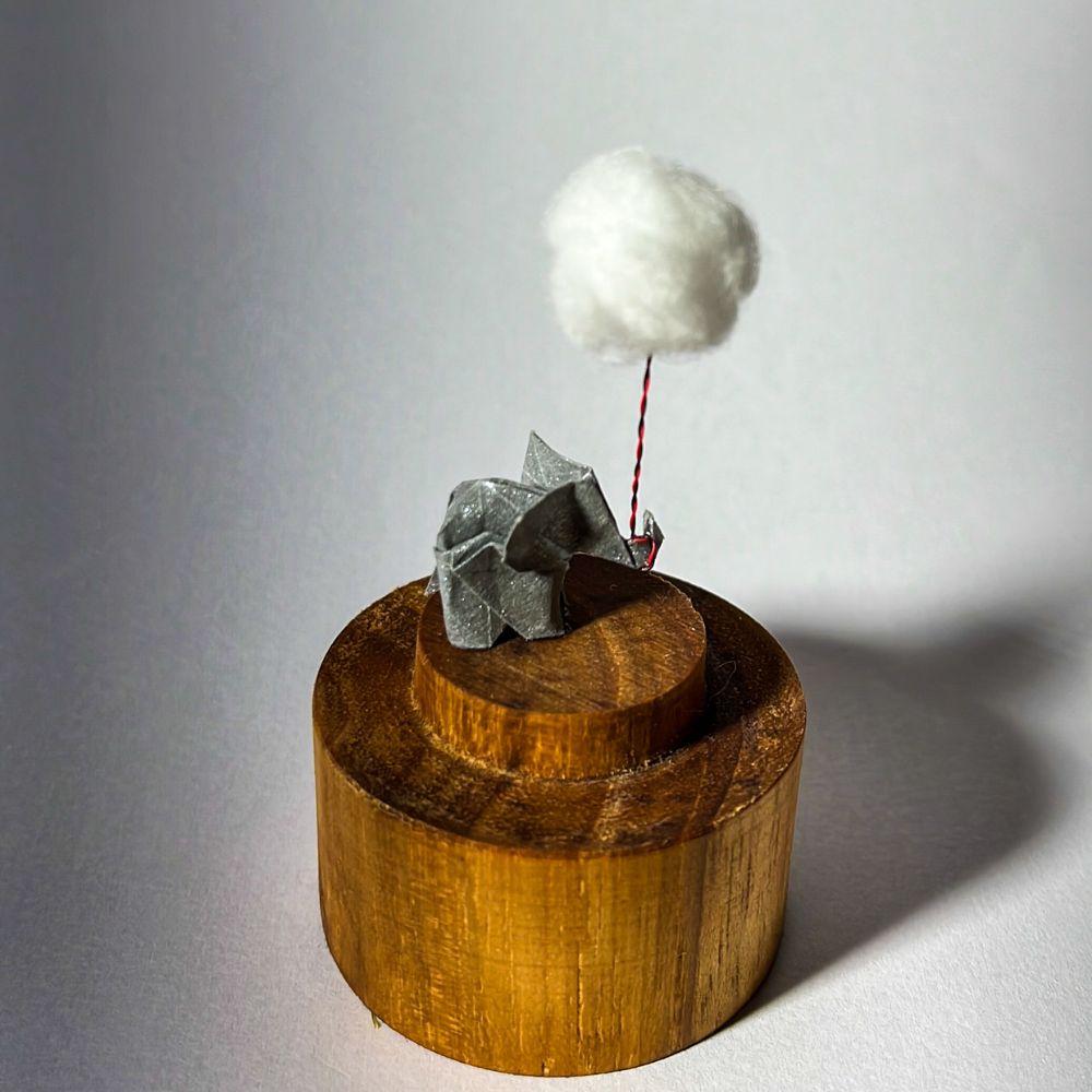 Lámpara miniatura de elefante amarillo en origami sosteniendo una nube iluminada en domo de vidrio - Plicatorius.