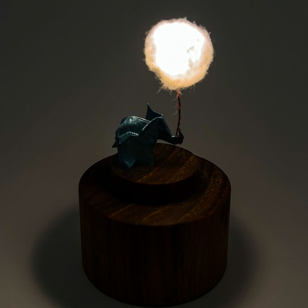 Lámpara miniatura de elefante amarillo en origami sosteniendo una nube iluminada en domo de vidrio - Plicatorius.