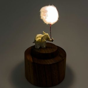 Lámpara miniatura de elefante amarillo en origami sosteniendo una nube iluminada en domo de vidrio - Plicatorius.
