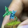 Colibrí verde en origami sobre flor amarilla miniatura en cúpula de vidrio - Artesanía Plicatorius Colombia.