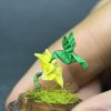 Colibrí verde en origami sobre flor amarilla miniatura en cúpula de vidrio - Artesanía Plicatorius Colombia.