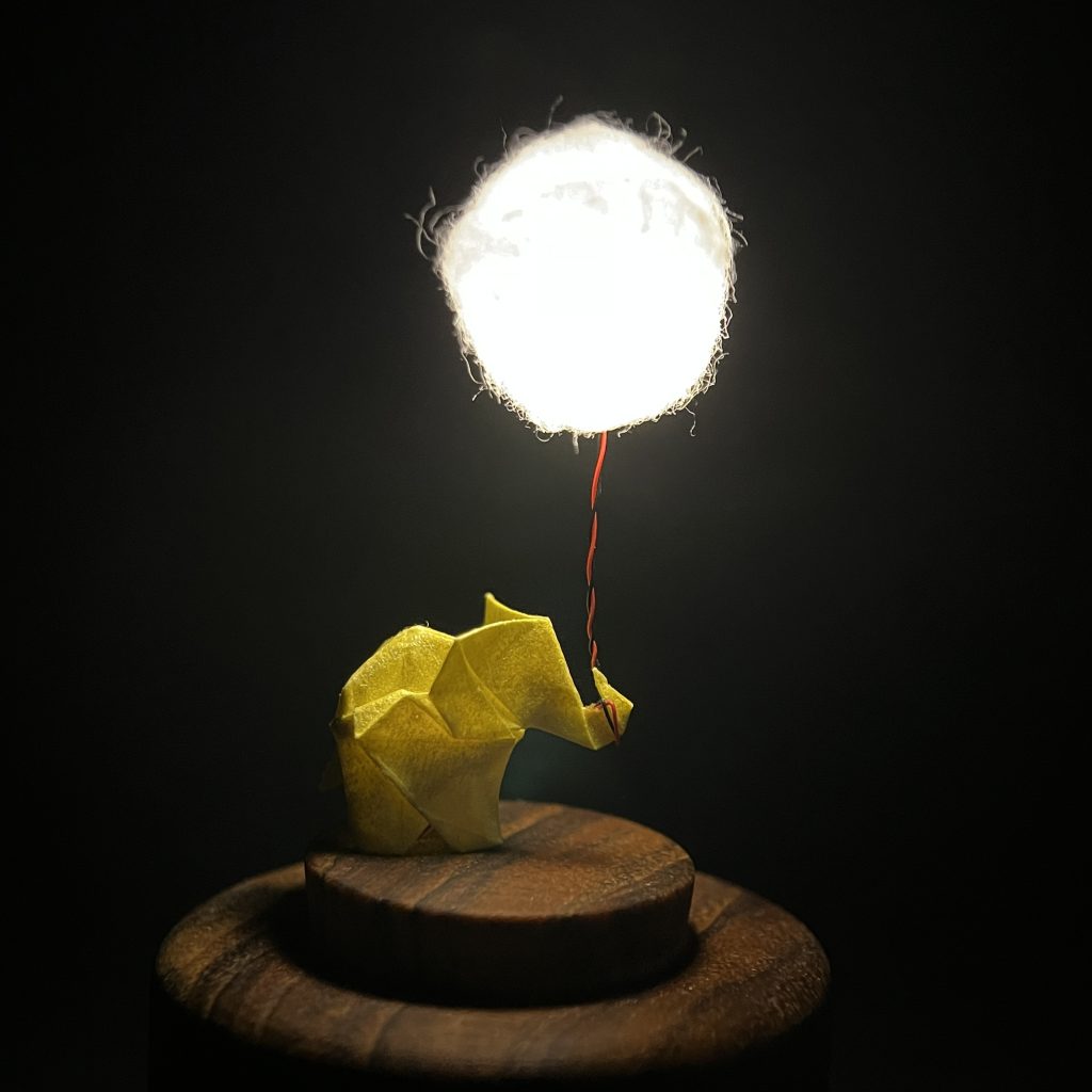 IMG_3189 Lámpara miniatura de elefante amarillo en origami sosteniendo una nube iluminada en domo de vidrio - Plicatorius.