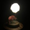Lámpara miniatura de elefante amarillo en origami sosteniendo una nube iluminada en domo de vidrio - Plicatorius.