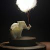 Lámpara miniatura de elefante amarillo en origami sosteniendo una nube iluminada en domo de vidrio - Plicatorius.