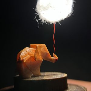 Lámpara miniatura de elefante amarillo en origami sosteniendo una nube iluminada en domo de vidrio - Plicatorius.