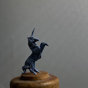 Unicornio de origami miniatura sobe base de madera