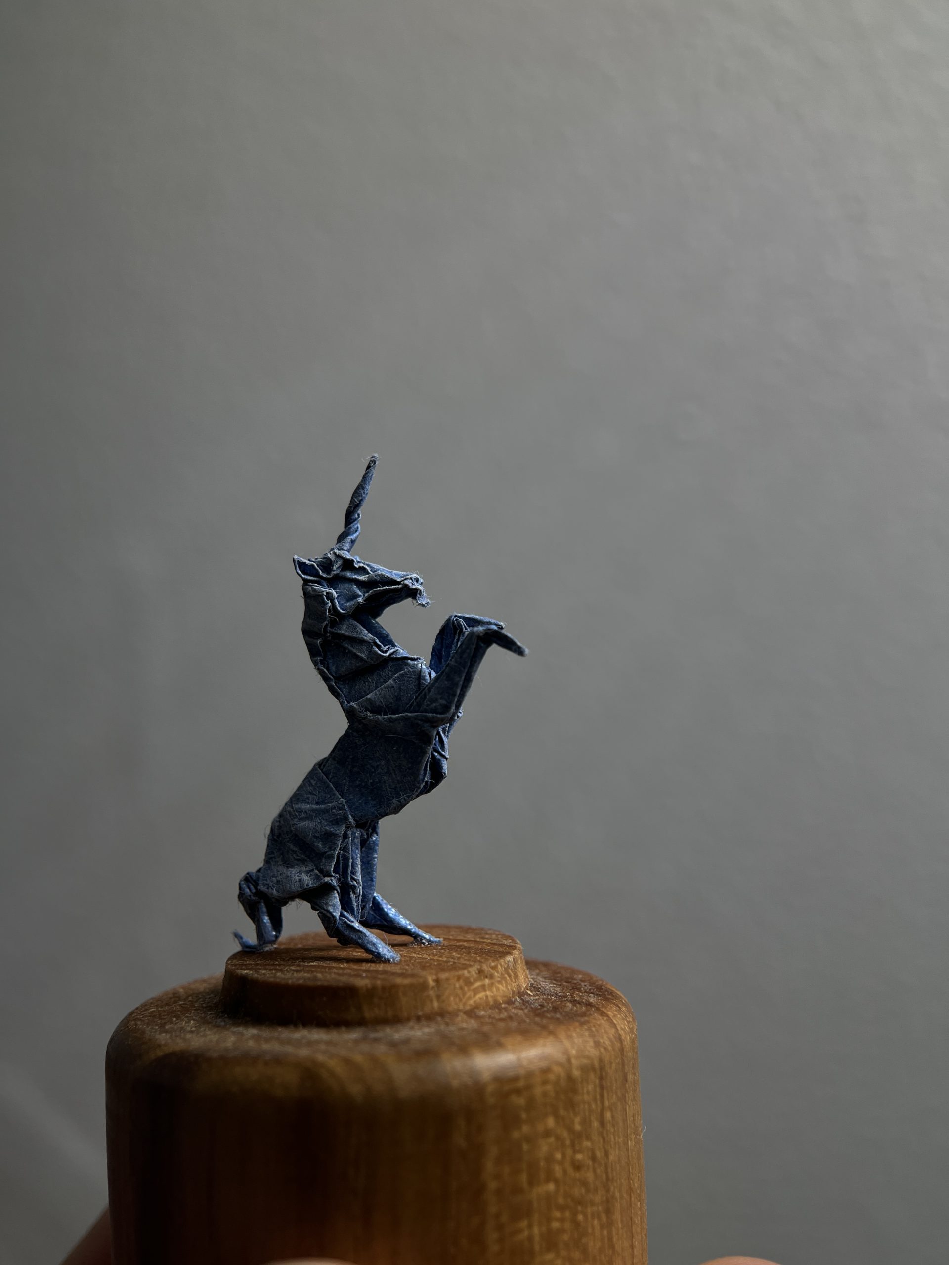 Unicornio de origami miniatura sobe base de madera